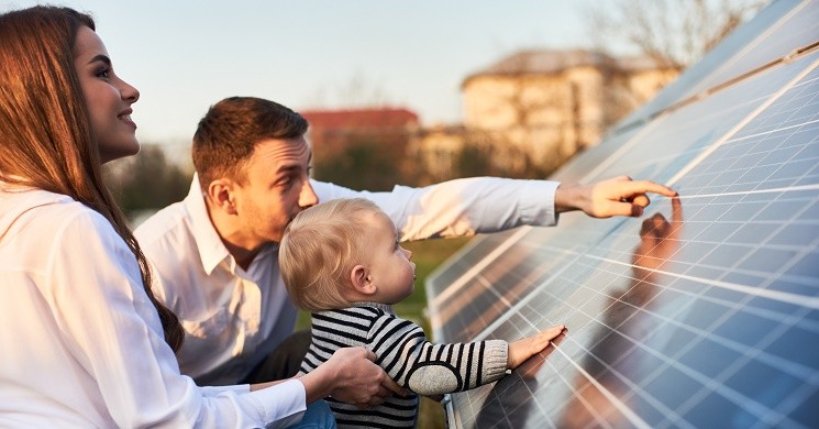 A young family pointing to solar panels in their yard